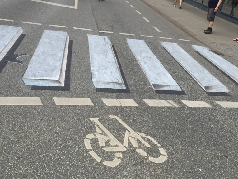 Mit Kreide auf die Straße gemalter Zebrastreifen wirkt dreidimensional.