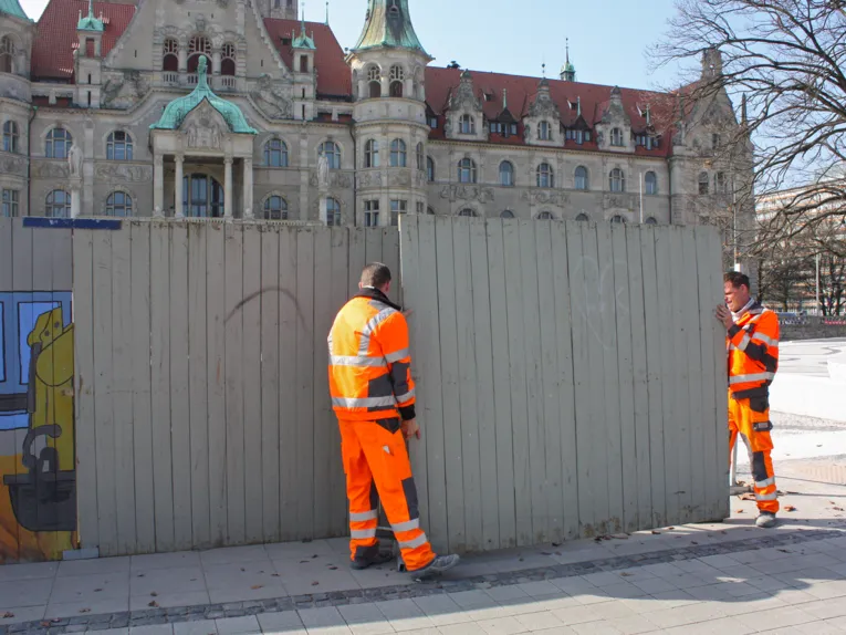 Zwei Arbeiter demontieren den Bauzaum am Trammplatz
