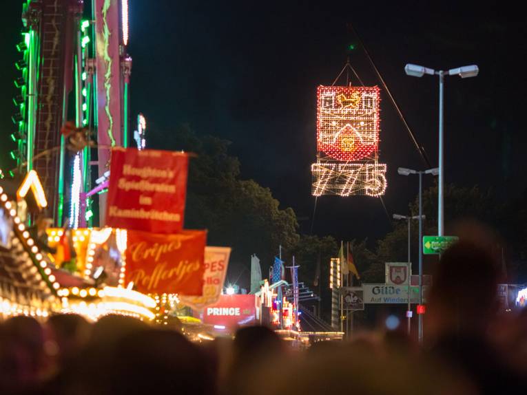 Das Stadtwappen Hannovers und die Zahl 775 leuchten in der Dunkelheit über dem Schützenplatz