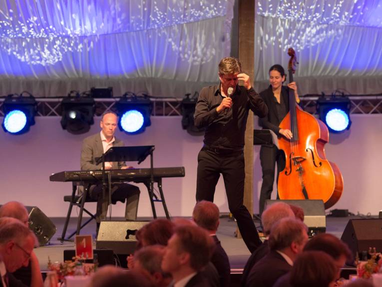Juliano Rossi mit Keyboarder und Musikerin mit Kontrabass auf der Bühne des Festzeltes Marris