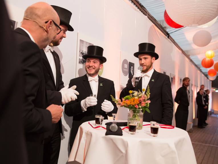 Moderator Andreas Kuhnt und ehemalige Bruchmeister trinken an einem Stehtisch Lüttje Lagen.