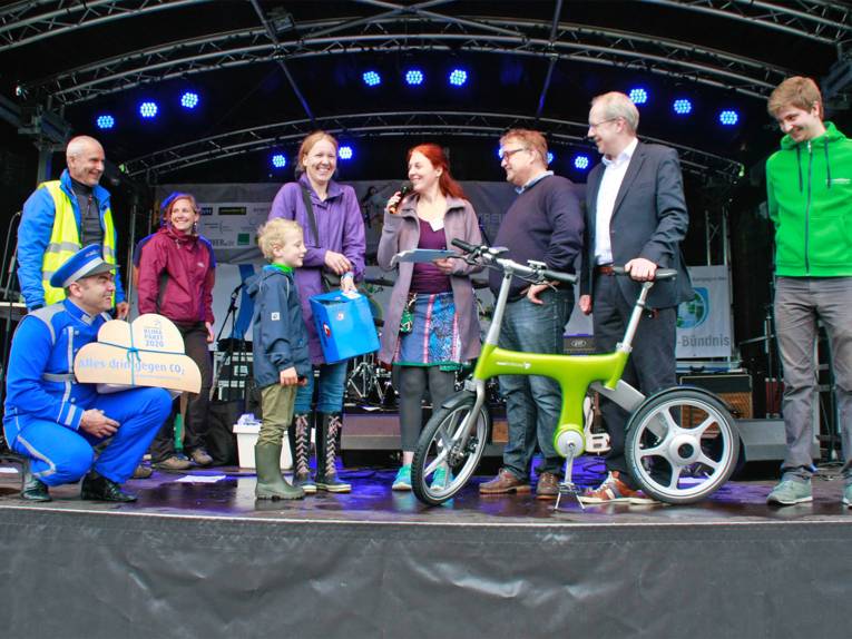 Ein Junge hat bei einer Verlosung ein Fahrrad gewonnen und nimmt seinen Preis auf der Bühne entgegen. Regionspräsident Hauke Jagau und Oberbürgermeister Stefan Schostok gratulieren.