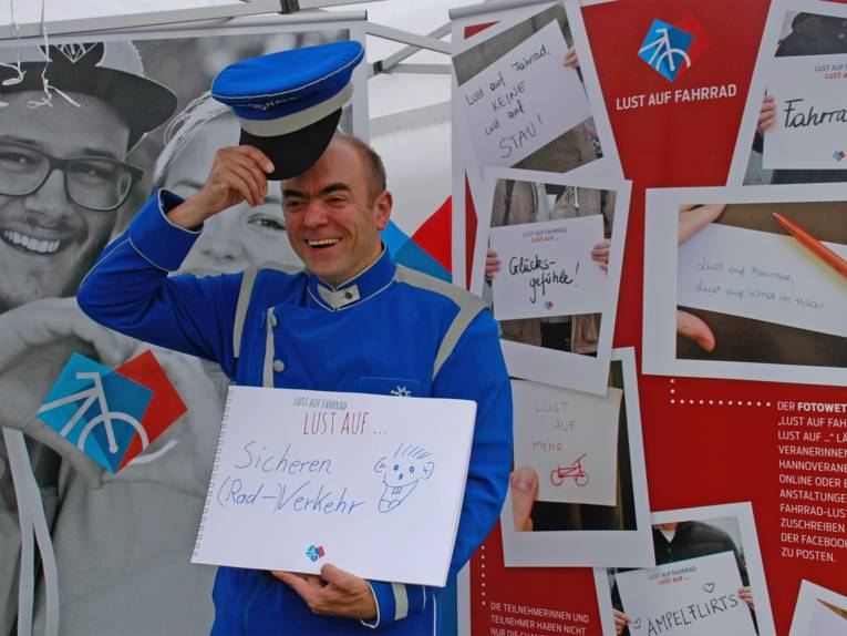 Mann mit Mütze macht vor einer Stellwand Werbung für die Aktion "Lust auf Fahrrad"