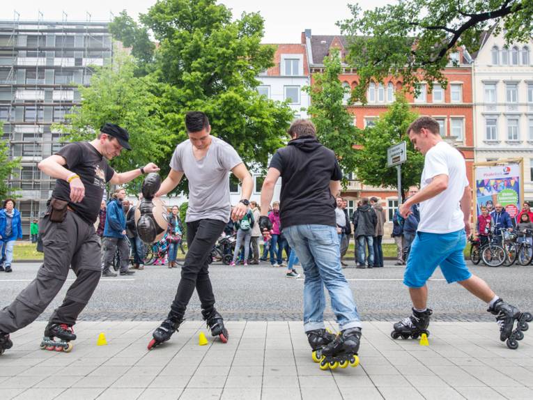Vier Rollschuhläufer zeigen ihr Können beim Geschicklichkeitsparkour vor Publikum am Friedrichswall