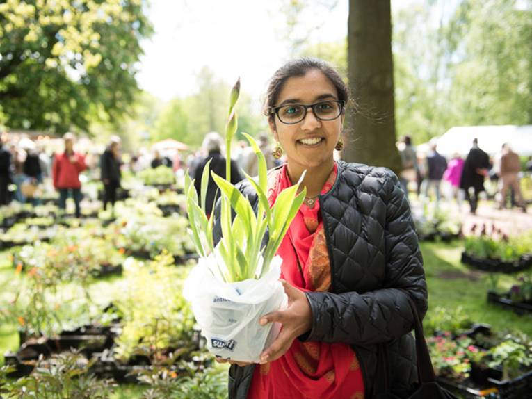 Junge Frau hält eine in eine Plastiktüte eingewickelte Pflanze in der Hand