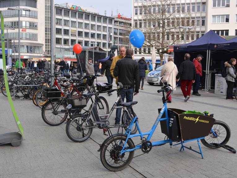 In der Fußgängerzone von Hannover sind zum Verkaufsoffenen Sonntag am 25. März 2018 eine Reihe von unterschiedlichen Elektro-Fahrrädern aufgebaut; Interessierte schlendern vorbei und lassen sich informieren.