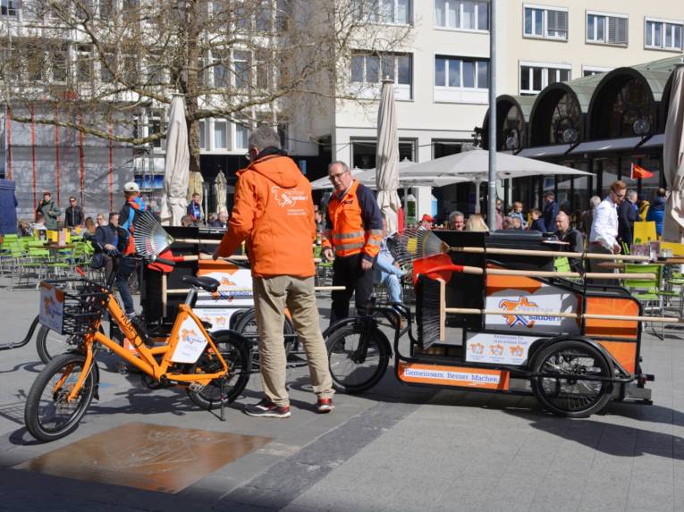 Beteiligte von "Hannover sauber" stehen mit zwei Lasten-Pedelecs von aha vor dem Cafe Kröpcke.