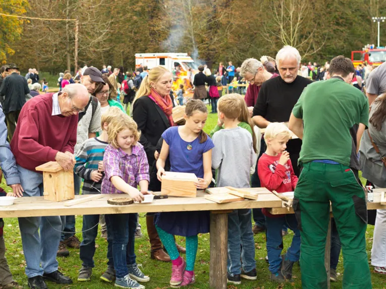 An provisorischen Holztischen bauen Kinder und Erwachsene unter Anleitung Nistkästen zusammen