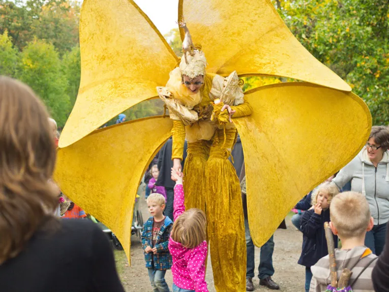 Eine fantasievoll kostümierte Schauspielerin begrüßt ein kleines Kind