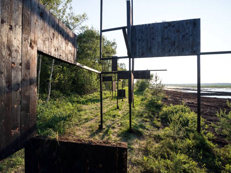 Installation mit geometrisch angeordneten Linien und Flächen in der Moorvegetation.