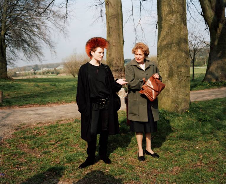 Junge Punkerin hält eine Hand auf, ältere Frau greift in ihre Handtasche.