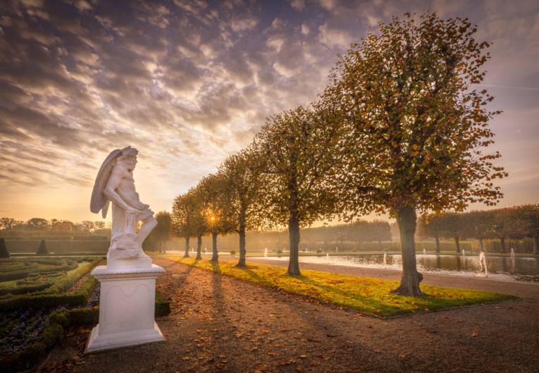 Die Sonne geht unter und die Herbstblätter fallen im Großen Garten.