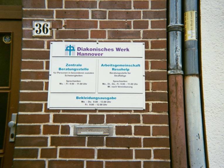 Fotografie, die eine Hauswand zeigt, an der ein Diakonie-Schild hängt. 