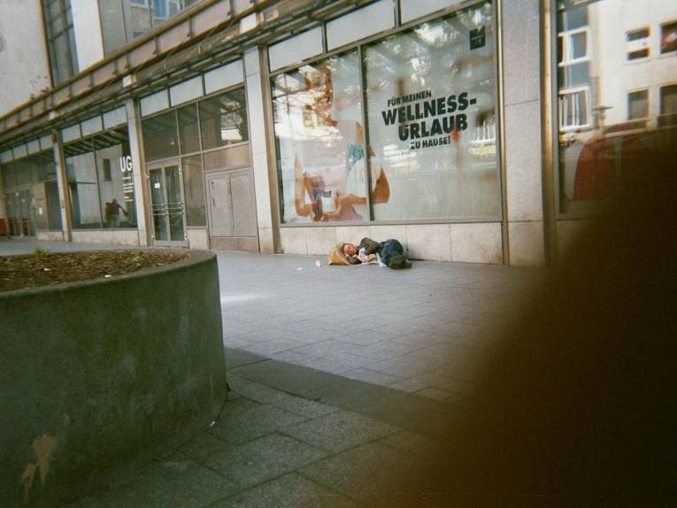 Foto, das einen Mann zeigt, der in einer Einkaufszone liegt. 