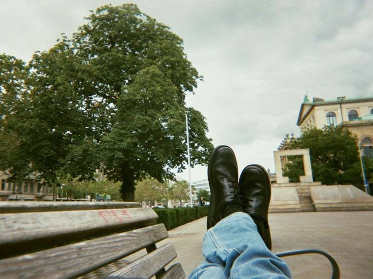 Fotografie, die einen Mann zeigt, der auf einer Bank liegt und die Füße lang gemacht hat. 