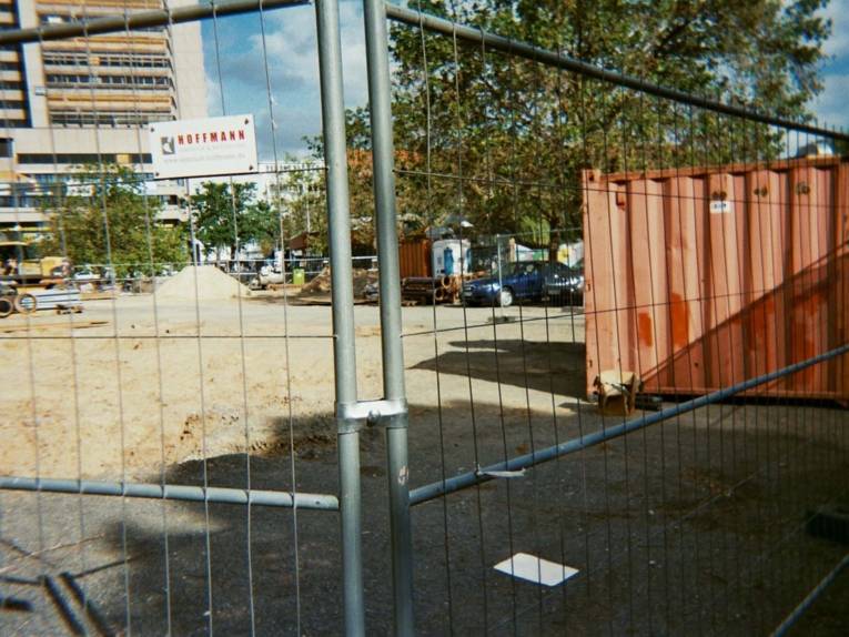 Foto, das, durch einen Zaun hindurch, einen leeren Platz zeigt. 