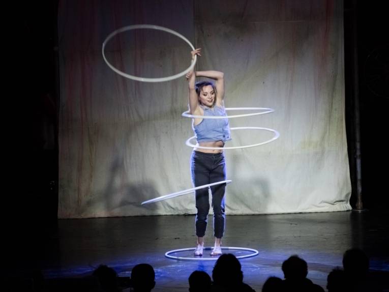 Hula-Hoop-Künstlerin auf einer Bühne.