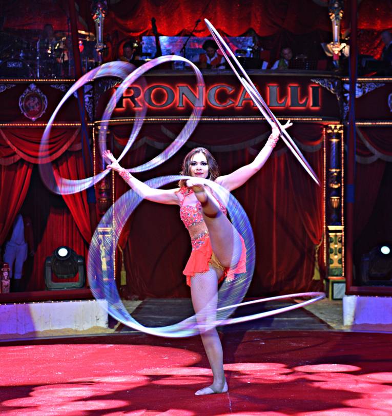 Frau jongliert mti Reifen an ihren Händen und Füßen