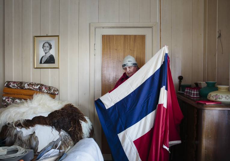 Frau steht in einem Schlafzimmer und hält eine Landesflagge in den Händen.