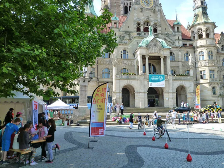 Ein Junge f&auml;hrt mit seinem Fahrrad im Slalom, um an gesteckten Markierungen vorbei zu kommen. Im Hintergrund warten weitere Kinder auf dem Trammplatz darauf, beim Fahrradparcours mitzumachen.