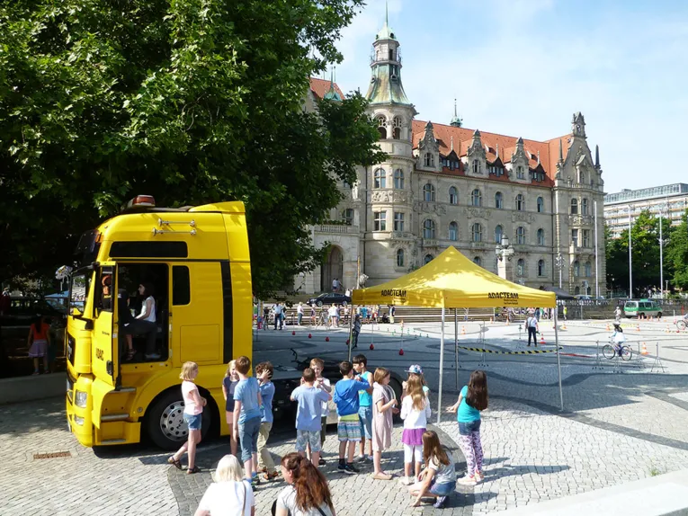 Kinder stehen im toten Winkel eines LKWs, das Kind im F&uuml;hrerhaus kann seine Schulkameradinnen und -kameraden nicht im R&uuml;ckspiegel sehen.