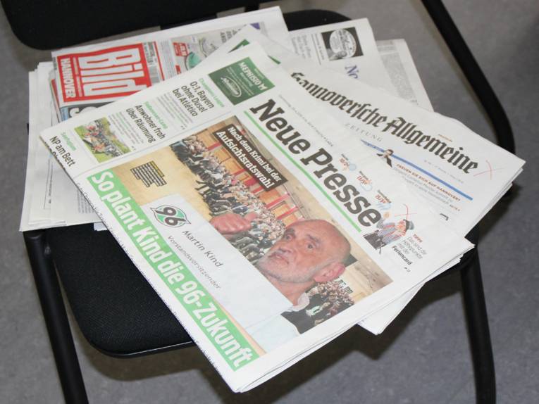 Auf einem Stuhl liegen mehrere Tageszeitungen.
