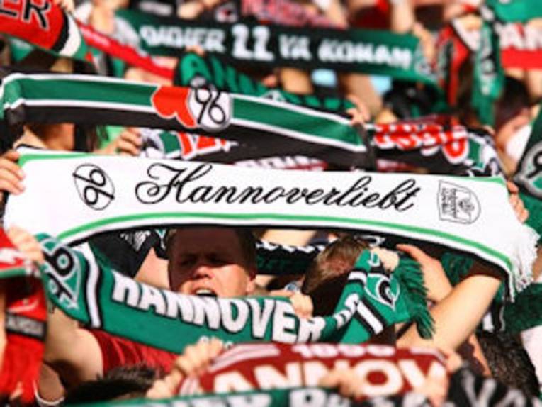 96-Fans halten ihre Schals in die Höhe.