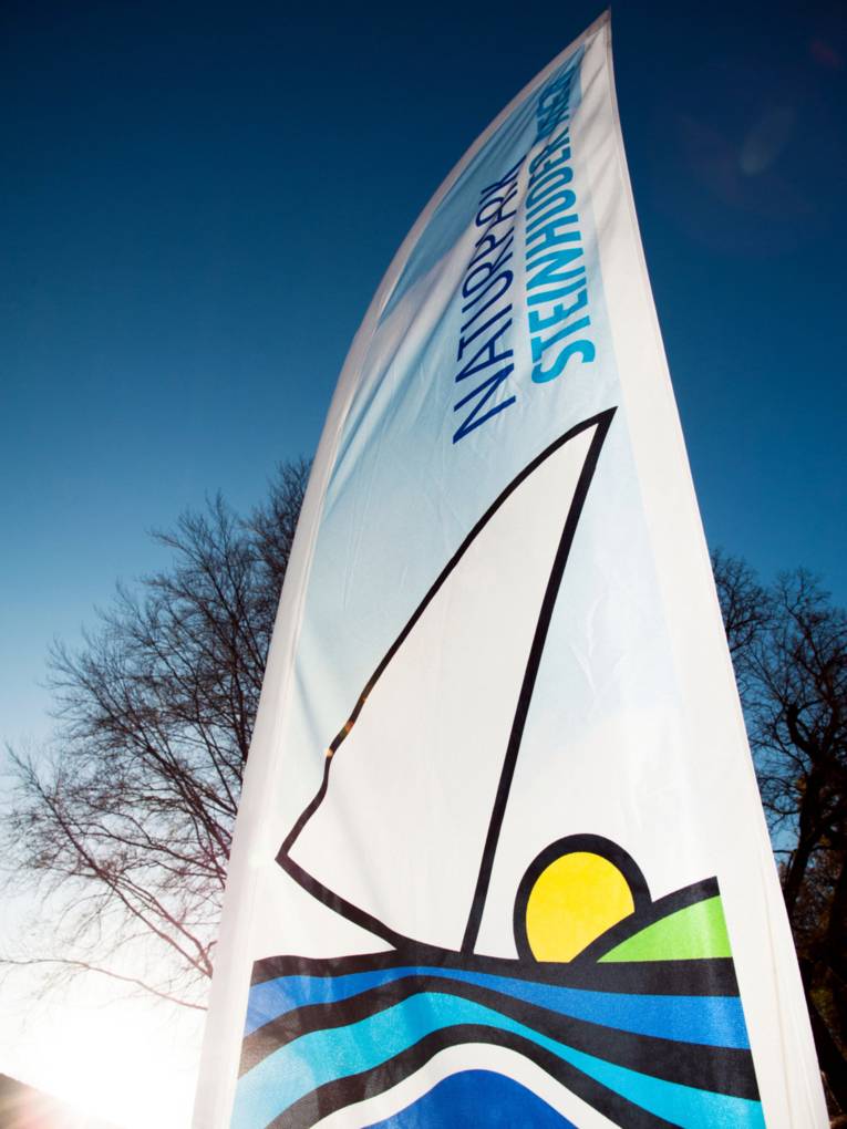 Freistehende Fahne mit dem Logo des Naturparks Steinhuder Meer