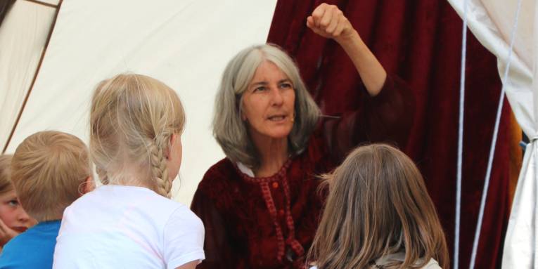 Eine Frau sitzt in einem Zelt und erzählt Kindern ein Märchen.