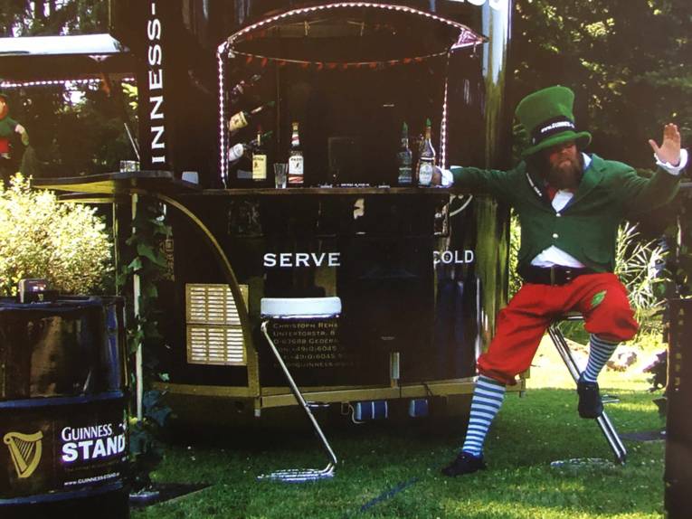 Mann in einem Koboldkostüm an einer Bierbude. 