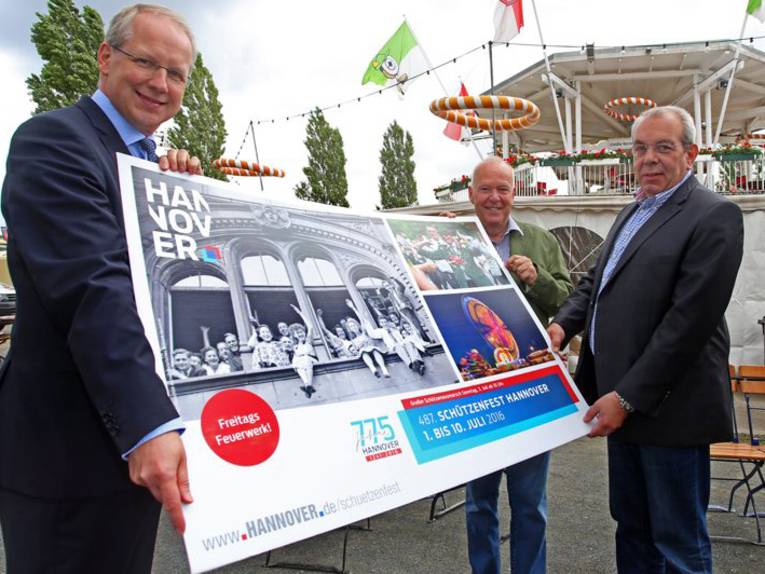 Drei Männer mit einem Plakat. 