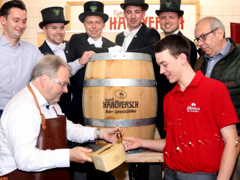 Acht Männer um ein Bierfass. 