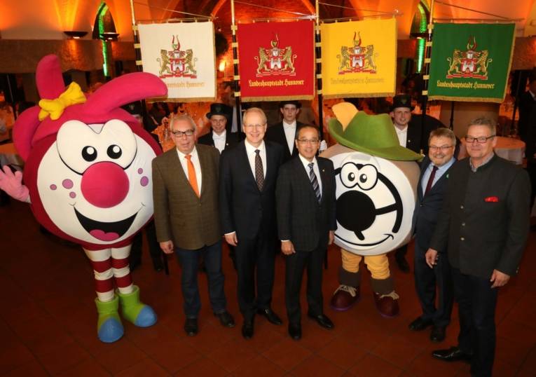Neun Männer mit zwei Maskottchen. 