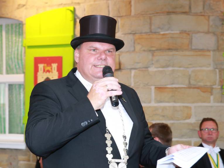 Männer in Cut und Zylinder auf einem Festplatz und in einem Zelt. 
