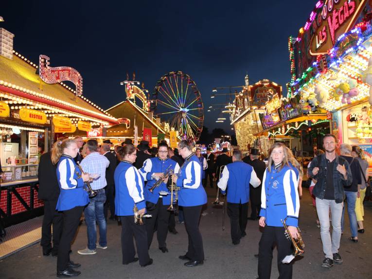 Männer in Cut und Zylinder auf einem Festplatz und in einem Zelt. 