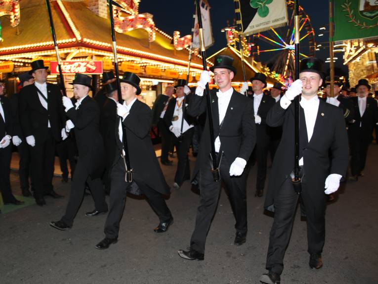 Männer in Cut und Zylinder auf einem Festplatz und in einem Zelt. 