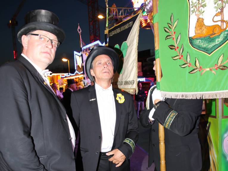 Männer in Cut und Zylinder auf einem Festplatz und in einem Zelt. 