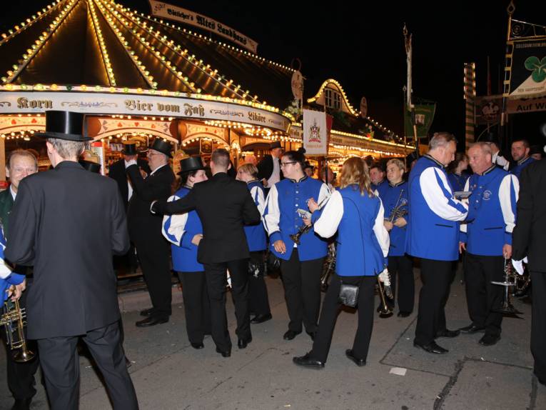 Männer in Cut und Zylinder auf einem Festplatz und in einem Zelt. 