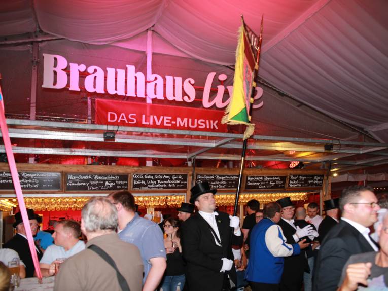 Männer in Cut und Zylinder auf einem Festplatz und in einem Zelt. 