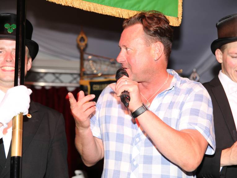 Männer in Cut und Zylinder auf einem Festplatz und in einem Zelt. 