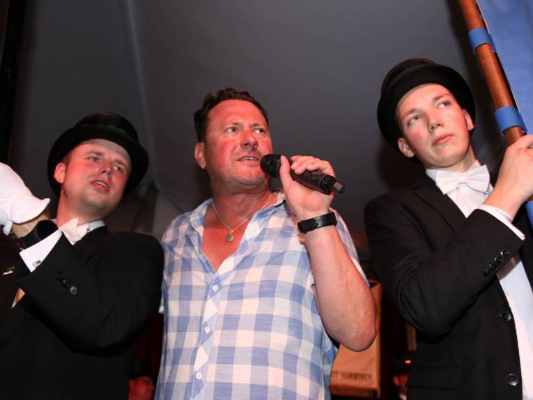 Männer in Cut und Zylinder auf einem Festplatz und in einem Zelt. 