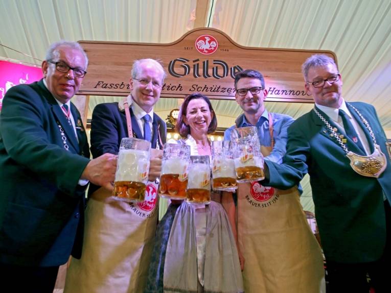 Vier Männer und eine Frau an einem Bierfass. 