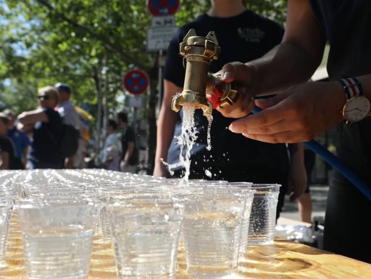 Becher, die gerade mit Wasser befüllt werden. 