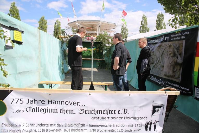 Menschen an einem Schießstand und in einer Festhalle. 