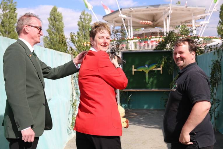 Menschen an einem Schießstand und in einer Festhalle. 