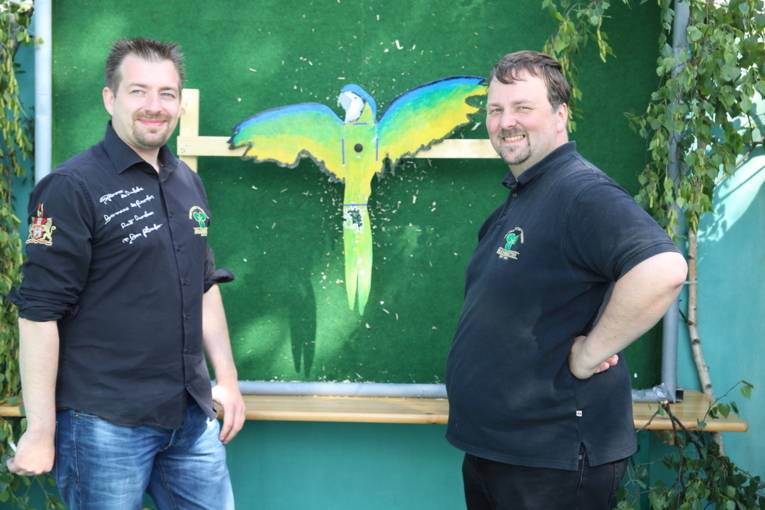 Menschen an einem Schießstand und in einer Festhalle. 