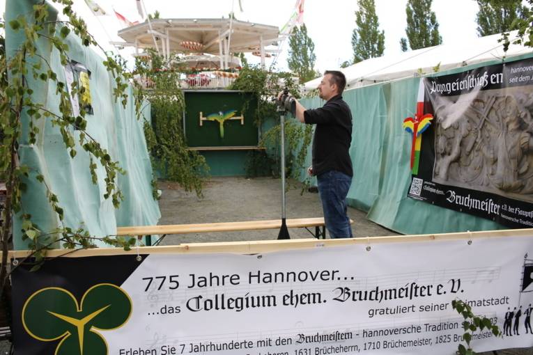 Menschen an einem Schießstand und in einer Festhalle. 