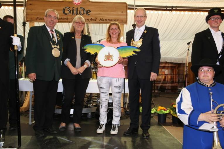 Menschen an einem Schießstand und in einer Festhalle. 