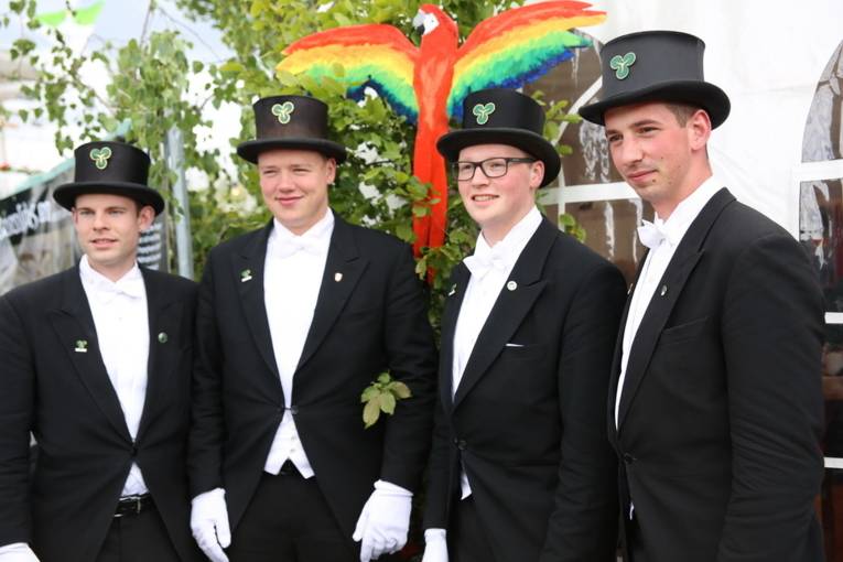 Menschen an einem Schießstand und in einer Festhalle. 