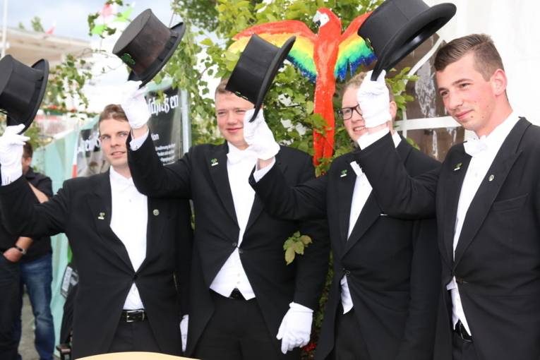 Menschen an einem Schießstand und in einer Festhalle. 